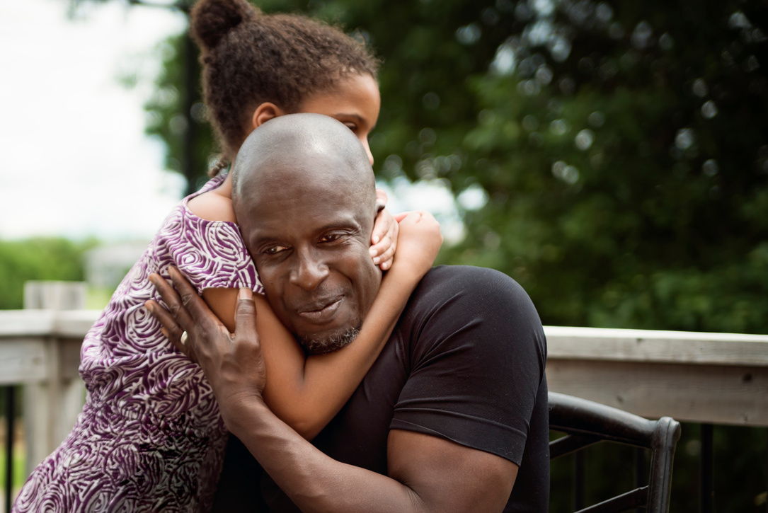 Young girl with autism hugging father outdoors.